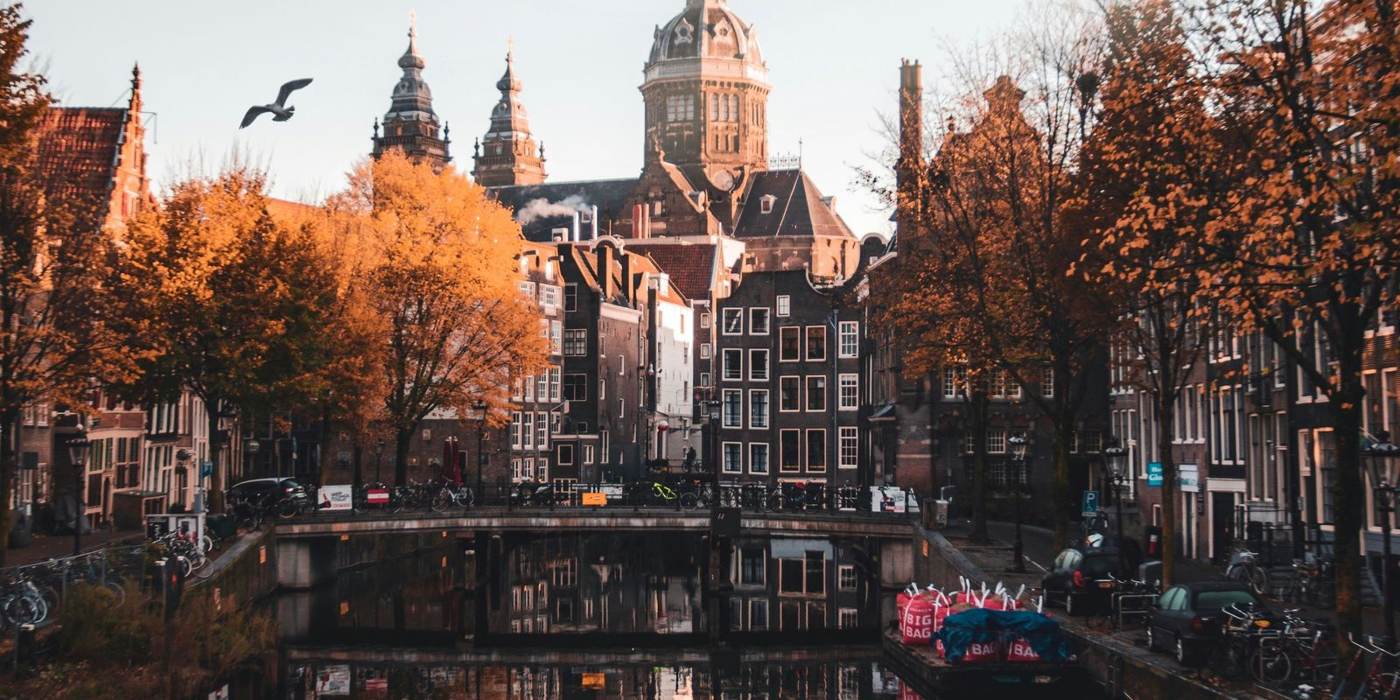 Un canal d'Amsterdam en automne, avec ses maisons anciennes et la basilique Saint-Nicolas
